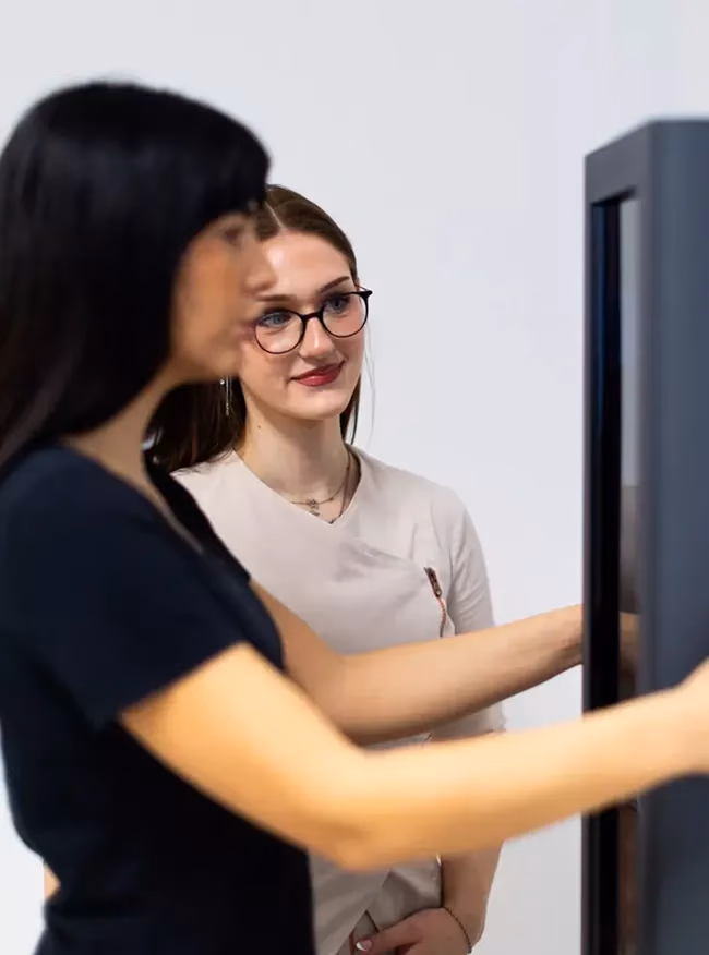 Beraterin begleitet eine Kundin bei der Messung am Visbody-Scanner