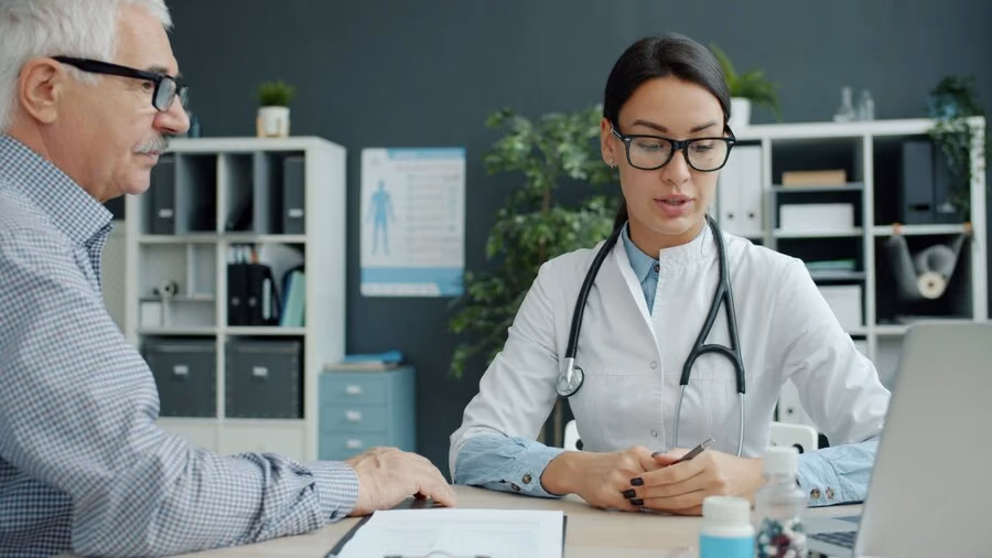 Ärztin im Gespräch mit einem älteren Patienten während eines Sarkopenie-Screenings
